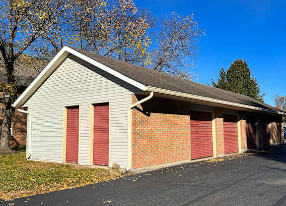 A garage with a grey roof and red doors.