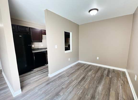 A kitchen with a black fridge and wooden flooring.