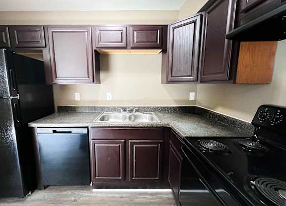 A kitchen with dark brown cabinets and black appliances.