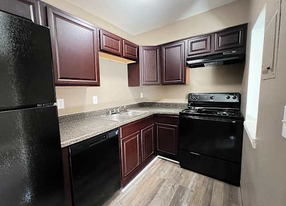 A kitchen with dark wood cabinets and black appliances.