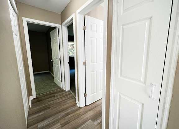 A hallway with white doors and a wooden floor.