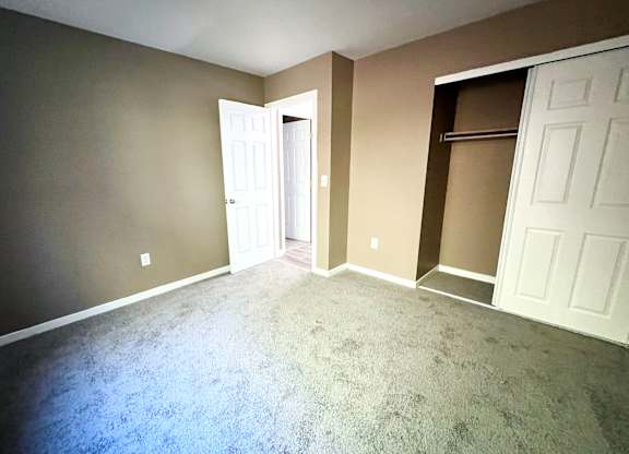 A room with a carpeted floor and two white doors.