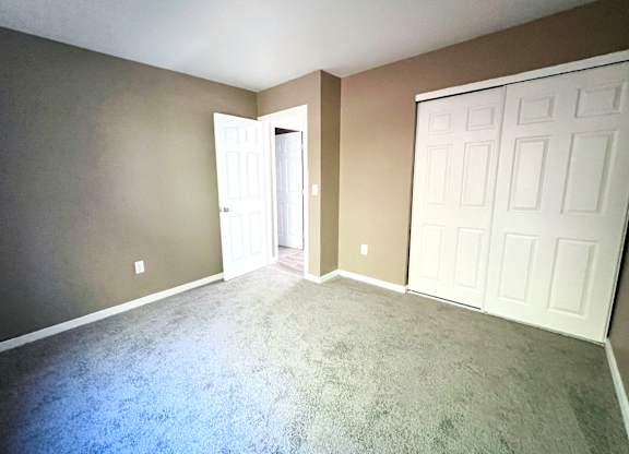 A room with a carpeted floor and a white door.