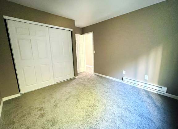 A room with a white door and carpeted floor.