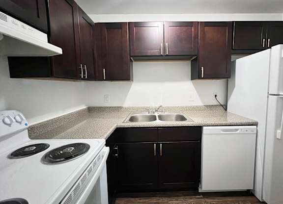 A kitchen with white appliances and dark brown cabinets.