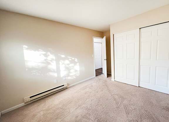 A room with a carpeted floor and two white doors.