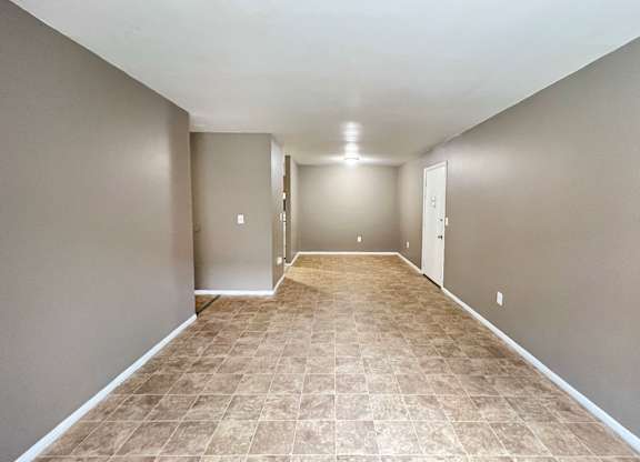 A long, empty hallway with tiled flooring and white walls.