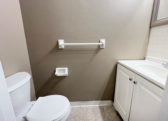 A white toilet sits next to a white sink in a small bathroom.