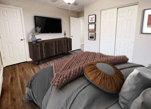 A bed with a grey comforter and a brown pillow with a round design on it.