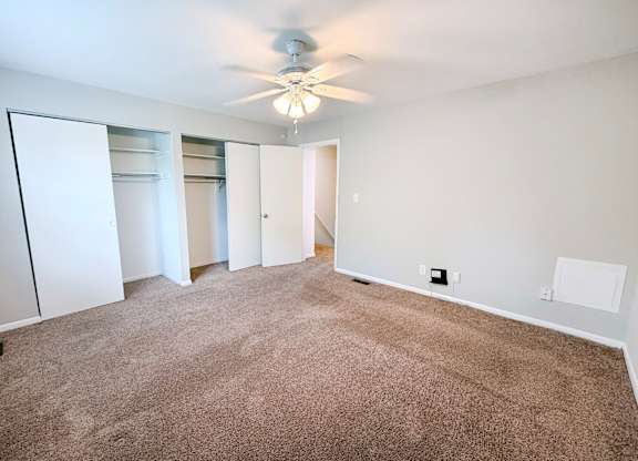 A room with a ceiling fan and carpeted floor.
