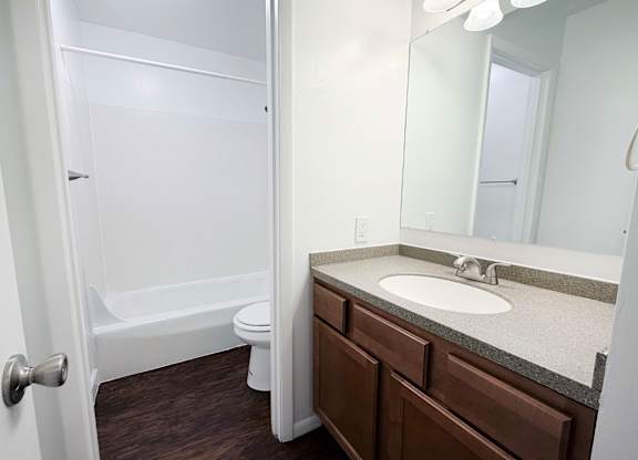 A white bathroom with a toilet, sink, and mirror.