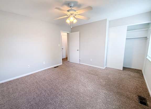 A room with a ceiling fan and carpeted floor.