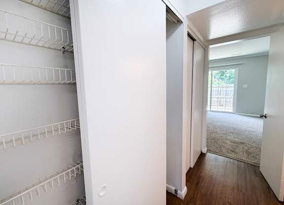 A white refrigerator with empty shelves in a room with a door leading to a hallway.