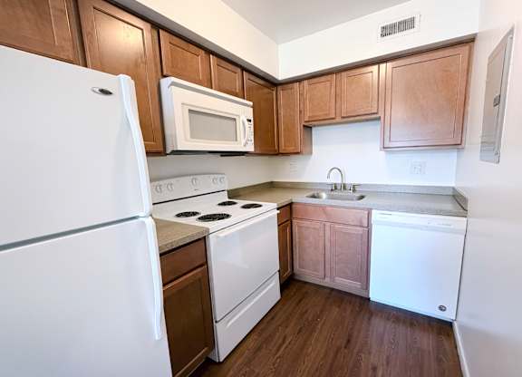 A kitchen with white appliances and wooden cabinets.