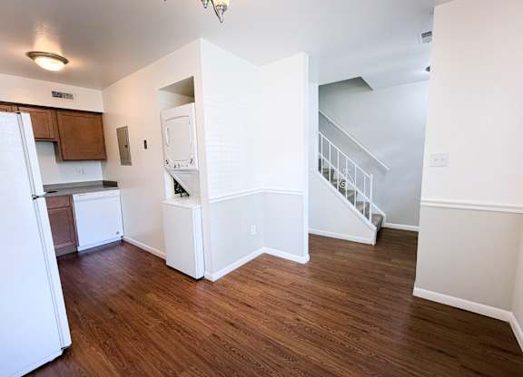 A kitchen with white appliances and wooden floors.