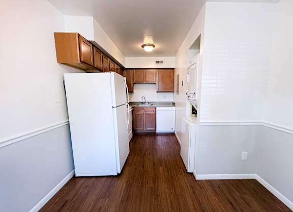 A kitchen with white appliances and wooden cabinets.