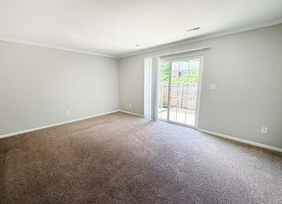 A room with a carpeted floor and a sliding glass door leading outside.