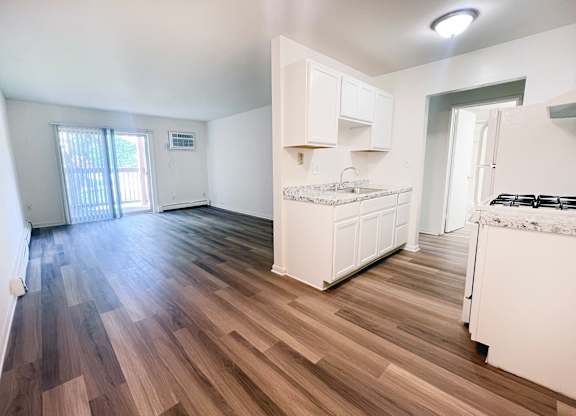 A kitchen with white cabinets and a wooden floor.