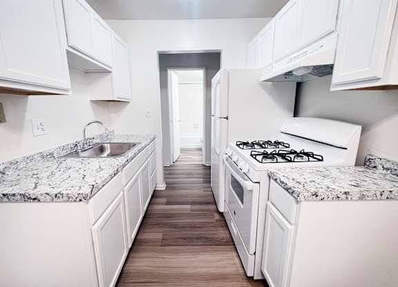 A kitchen with white cabinets and granite countertops.