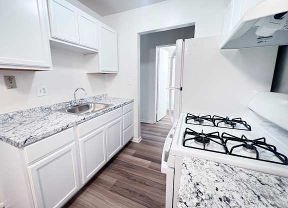 A kitchen with a marble countertop and white cabinets.