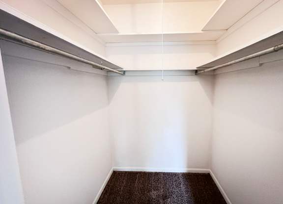 A long, narrow hallway with white walls and a brown carpeted floor.