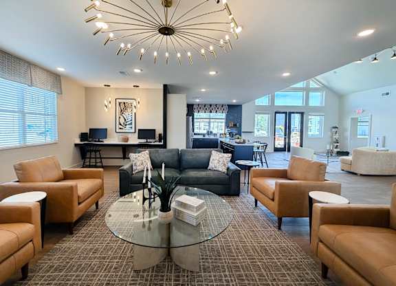 A living room with a glass table and leather chairs.