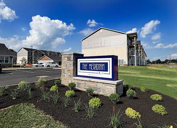 Property entrance sign with landscaping and parking area at The Meridian on 32 Apartments, Batavia, Ohio