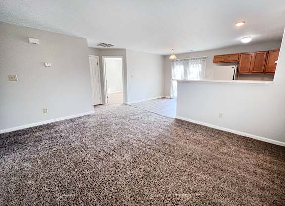 A large, empty room with carpeted flooring and white walls.