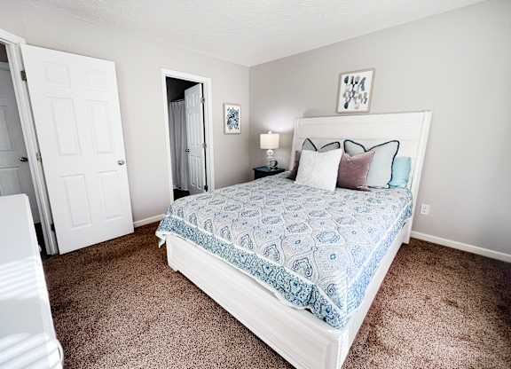 A bedroom with a bed, nightstand, and two doors.