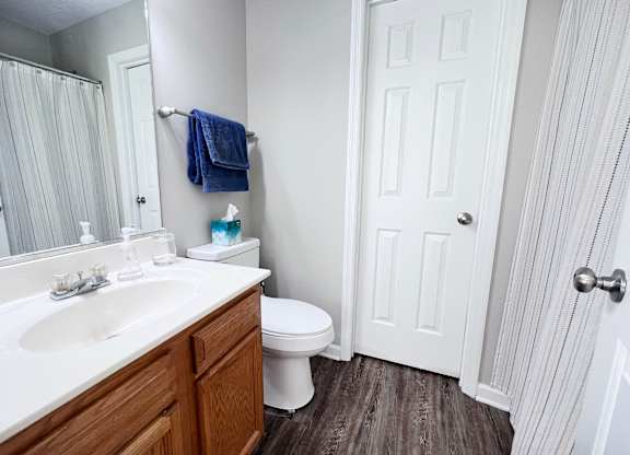 A white bathroom with a toilet, sink, and mirror.