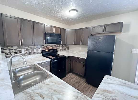 A kitchen with a black fridge and a black stove.