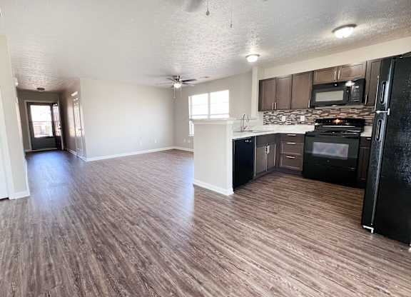 A kitchen with black appliances and wooden floors.