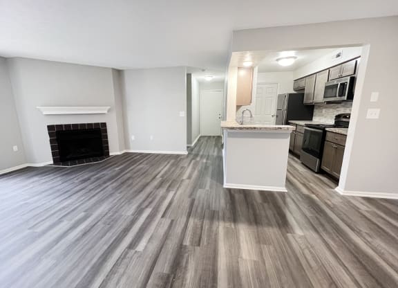 an empty living room with a fireplace and a kitchen  at Deercross Apartments, Cincinnati