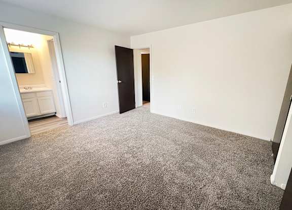 an empty living room with carpeting and a door to a bathroom at Four Worlds Apartments, Cincinnati, OH 45231