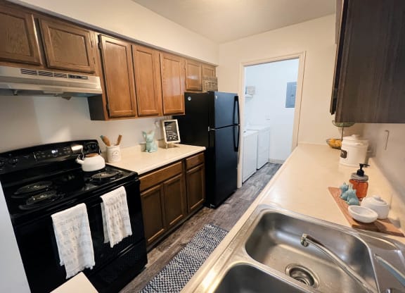 a kitchen with a black refrigerator freezer next to a stove top oven  at Steeplechase Apartments, Ohio, 45140