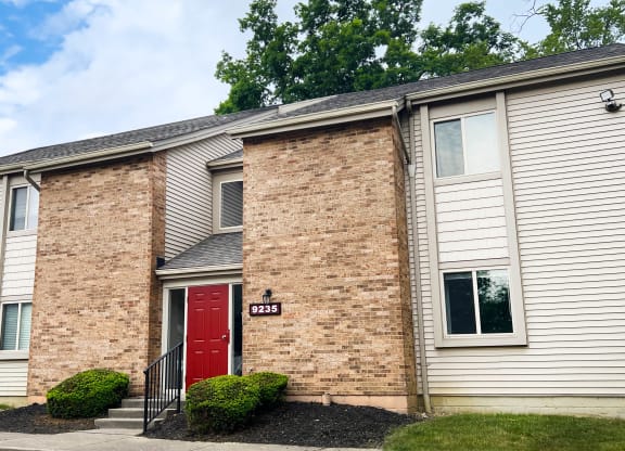 a brick building with a red door and white siding  at Hunter's Creek Apartments, Cincinnati, Ohio