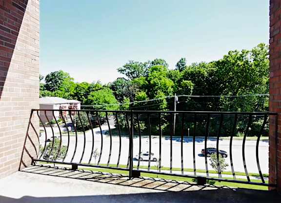 A black metal gate blocks the entrance to a driveway.