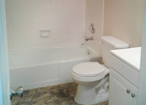 A white toilet sits next to a white cabinet in a bathroom.