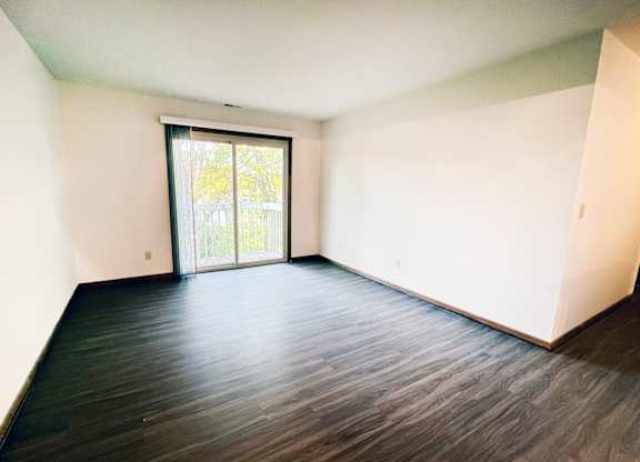 an empty living room with wood floors and a sliding glass door at Forest Creek Apartments, Ohio 45044