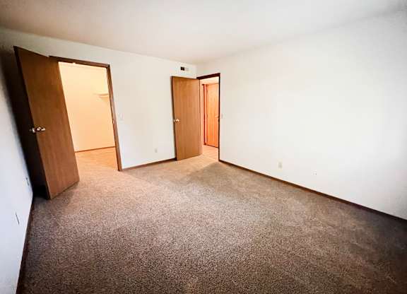 an empty room with a carpeted floor and two doors at Forest Creek Apartments, Middletown, OH