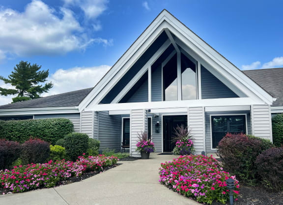 the front entrance of a white house with flowers and bushes at Deercross Apartments, Cincinnati, OH
