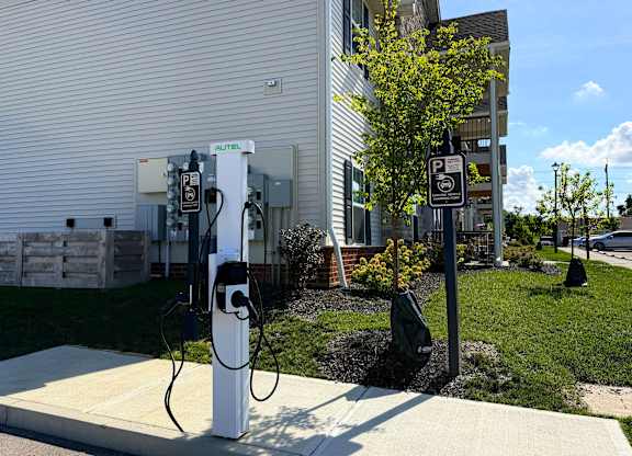 A parking sign is next to a charging station.