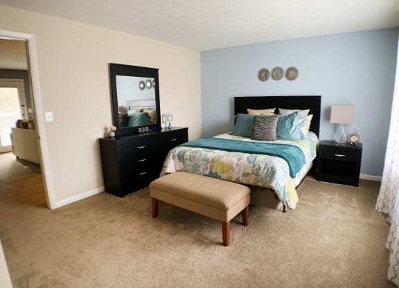 a bedroom with a bed and a dresser and a window at The Vinings Apartments, Cincinnati, 45245