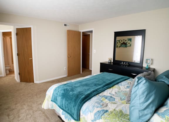 a bedroom with a bed and a mirror on the wall at The Vinings Apartments, Cincinnati, Ohio
