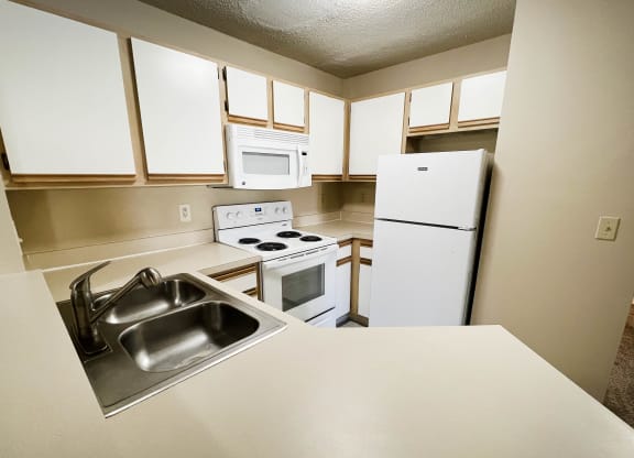 an empty kitchen with white cabinets and appliances and a sink at Eagle Crest Apartments, Galloway