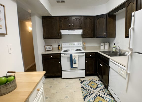 a kitchen with white appliances and dark wood cabinets at Knobs Pointe Apartments, Indiana