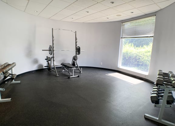 a gym with weights and a window in the corner of a room  at Knobs Pointe Apartments, New Albany, IN