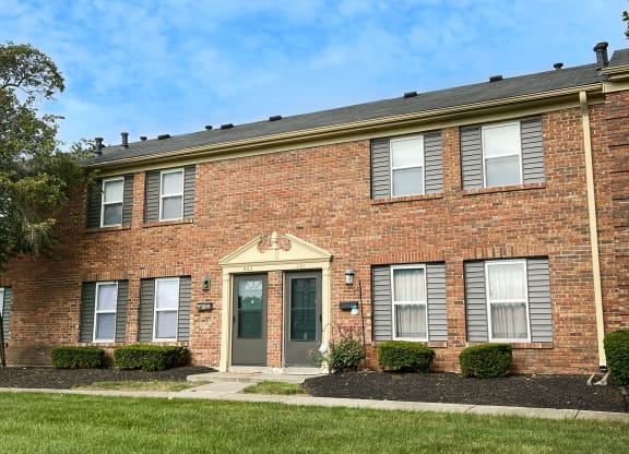 a brick building with a green door and grass at Revere Village Apartments, Centerville, Ohio