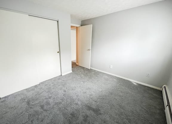 a bedroom with a carpeted floor and an open door  at Summit East - A Senior Community, Ohio, 45237