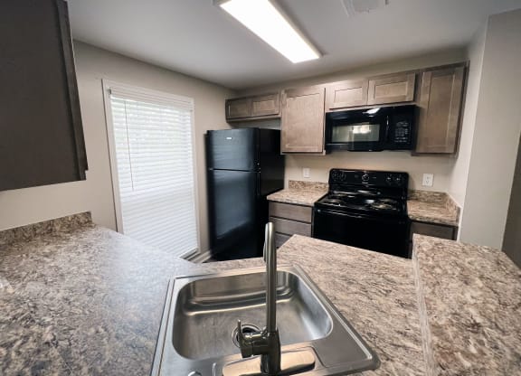 a kitchen with granite countertops and black appliances  at Woodhills Apartments, Ohio